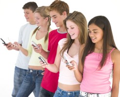 Row of five friends using cellular phones smiling